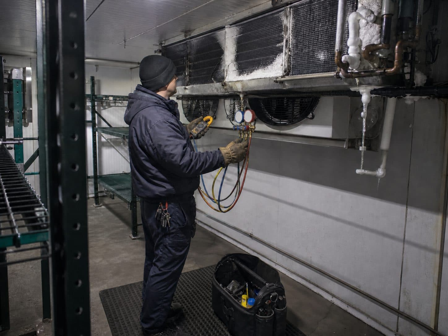 An iced-over evaporator coil being serviced inside a walk-in freezer