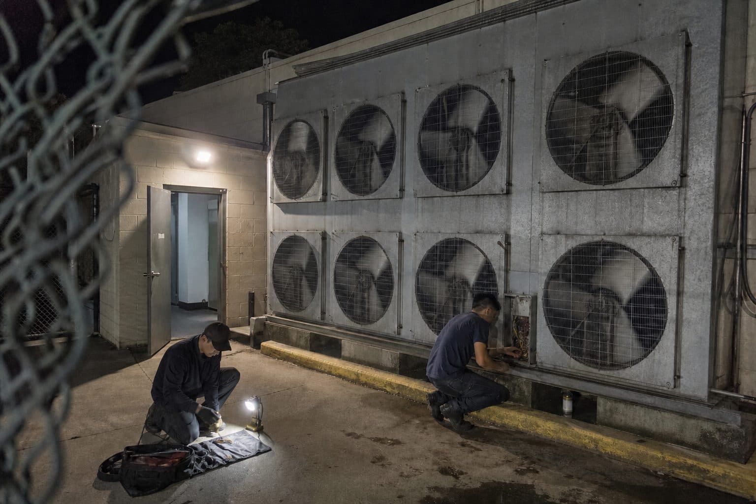 Technicians servicing supermarket rack condensers at night